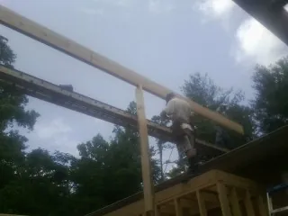 Carpenter setting a ridge beam over a new addition frame — Ice Dam Removal by Roofing Brothers in New Deal
