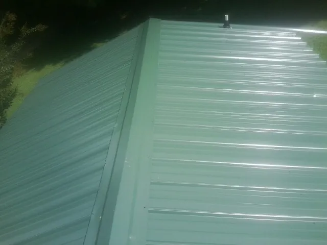 New green metal panels meeting at the ridge of a roof — Flat Roof Repair work by our crew in New Deal