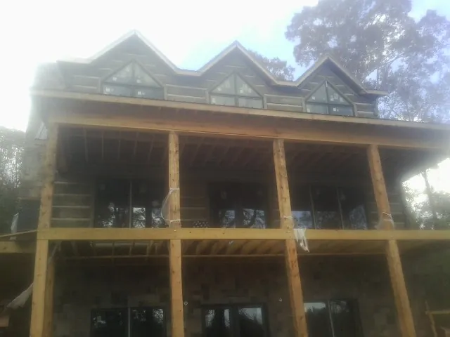 Dormers and porch framing on a large log home under construction — Roof Coating work by our crew in New Deal