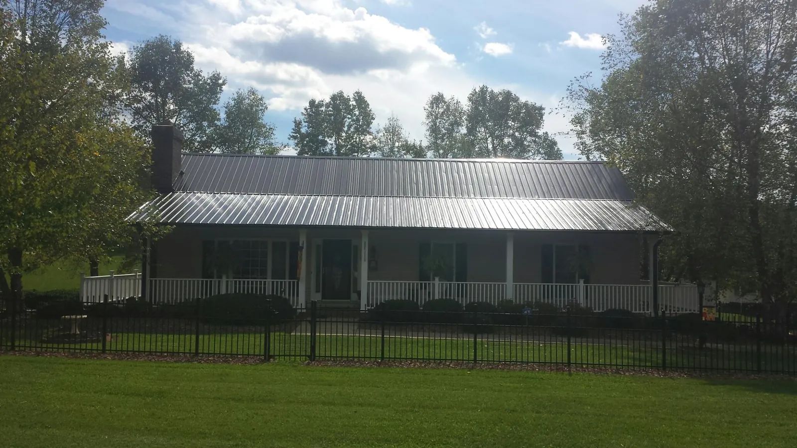 Gray metal roof on a brick ranch with a full width front porch — Gutter Guard Installation work by our crew in New Deal