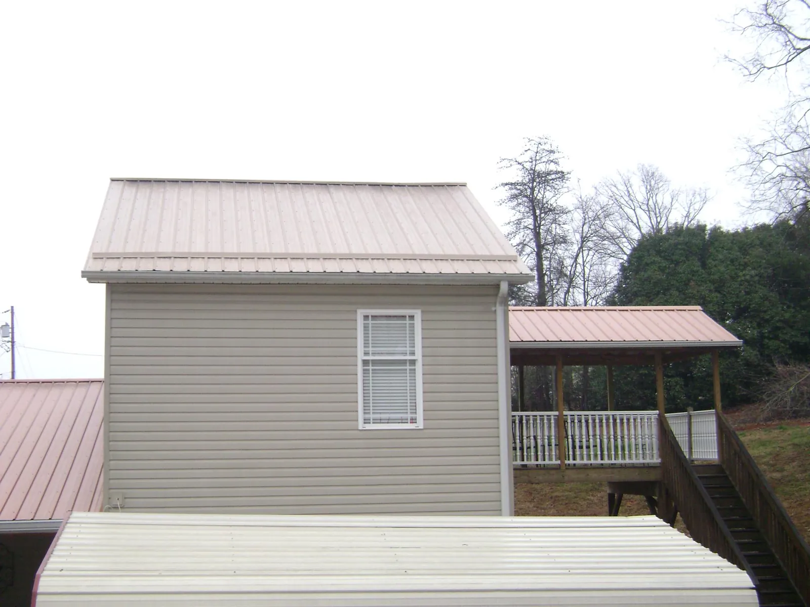 Tan metal roofs on a two story addition and attached porch, from a Roof Replacement job in New Deal