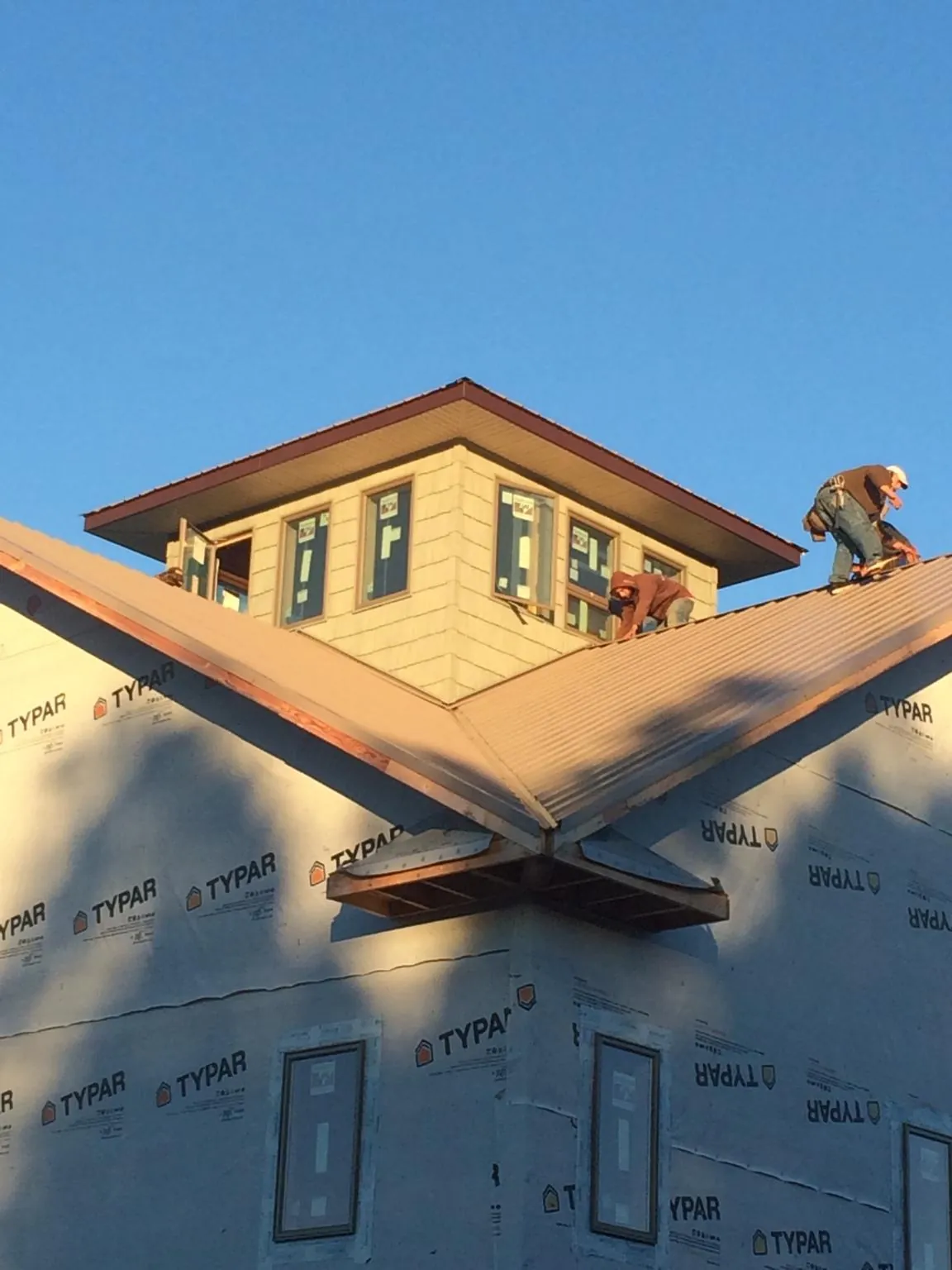 Roofers working around a rooftop cupola on a new metal roof at sunset — Roof Waterproofing in New Deal by Roofing Brothers
